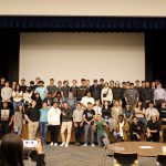 A group photo of 80 Core Plus Aerospace interns. The interns are standing on a stage.