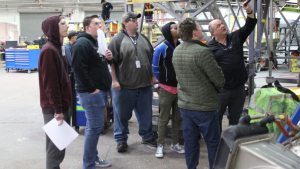 A group of students in a factory looking up. 