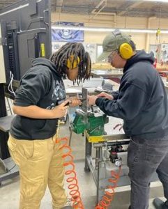 A photo of two students completing a hands-on project using power tool