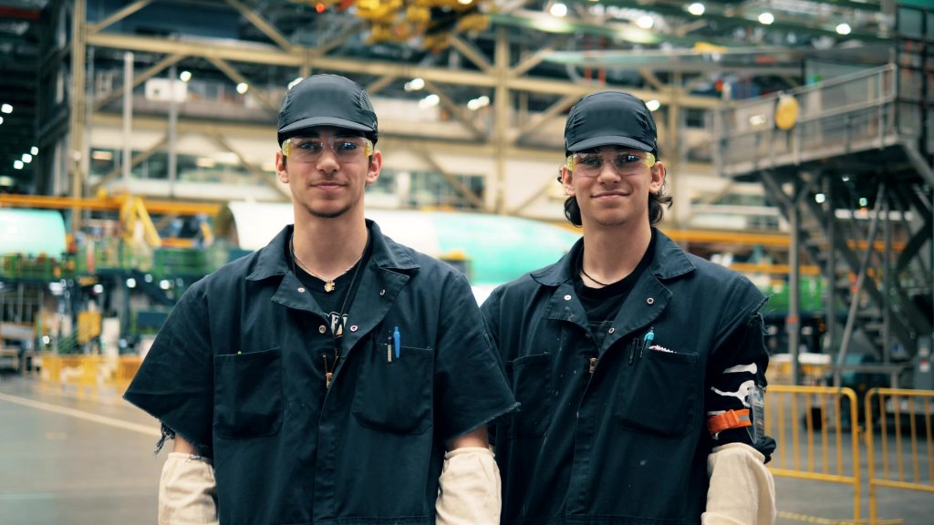 A photo of two workers inside of a factory.