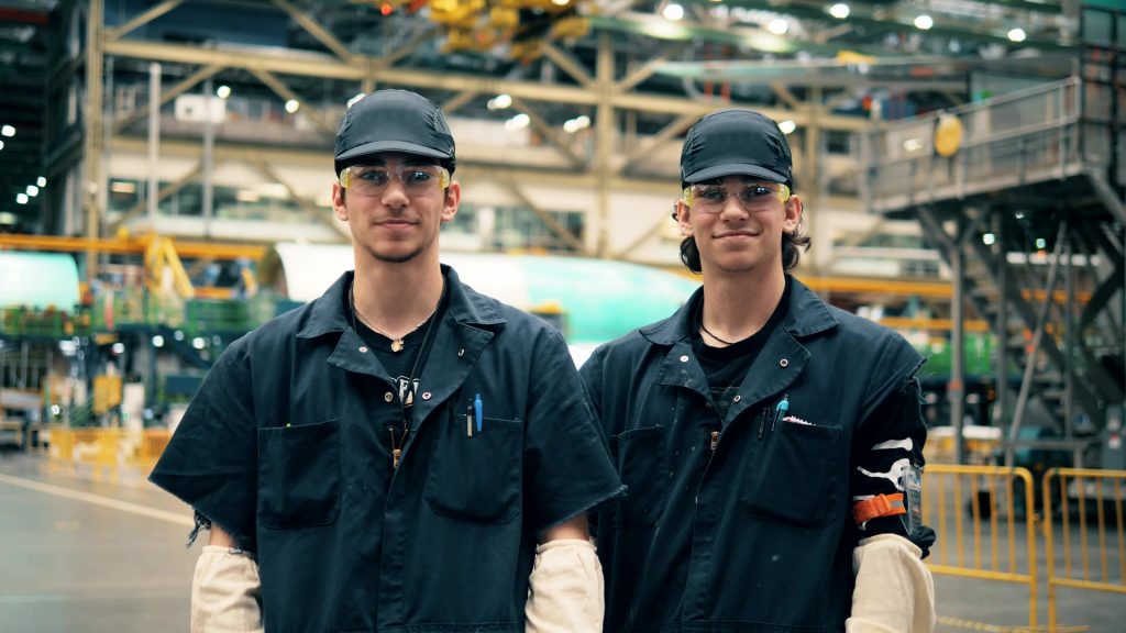 A photo of two workers inside of a factory. 