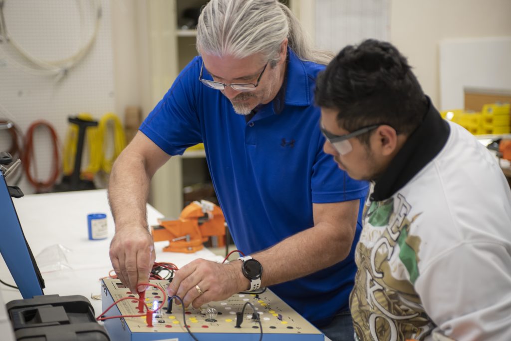 A teacher instructing a student how to do an electrical project