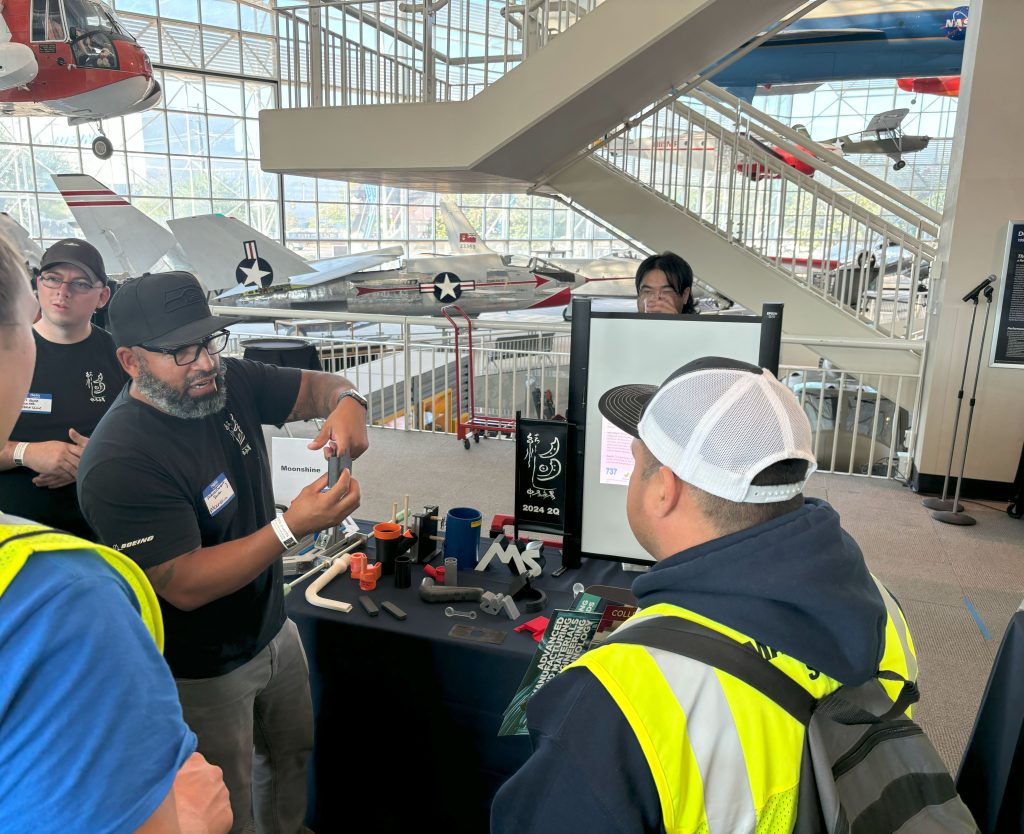 A person showing a student a person a part of a machine.